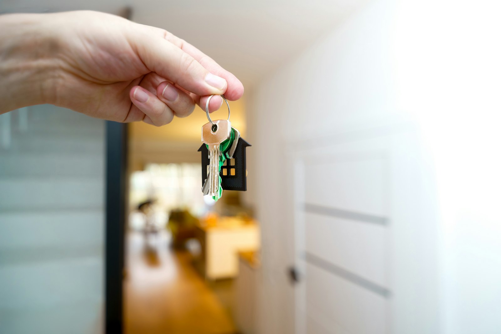 A hand holding a set of house keys at the front door of a home