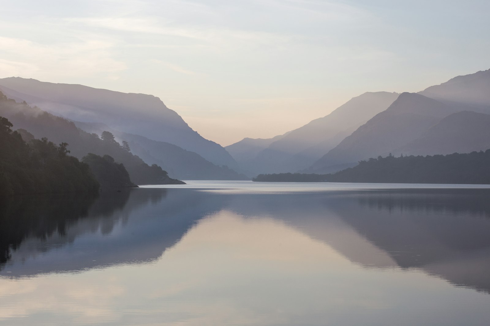 Still water reflecting the mountains around a lake at first light