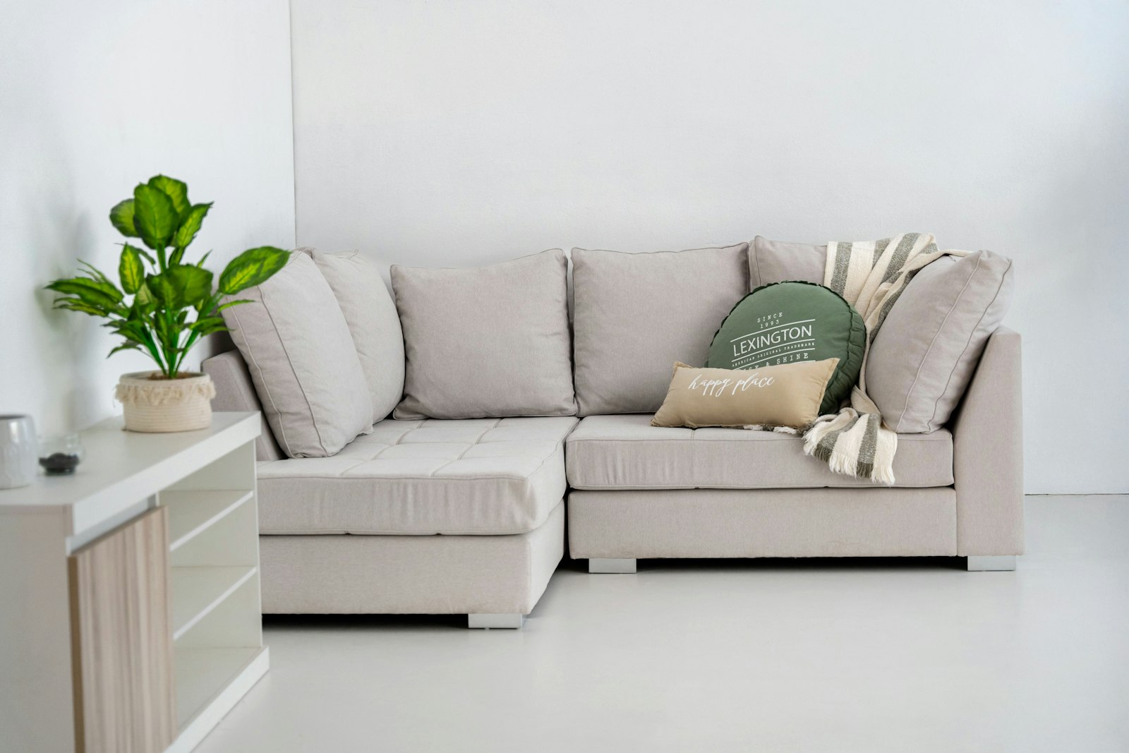 A light sectional sofa with pillows and a throw in a bright living room